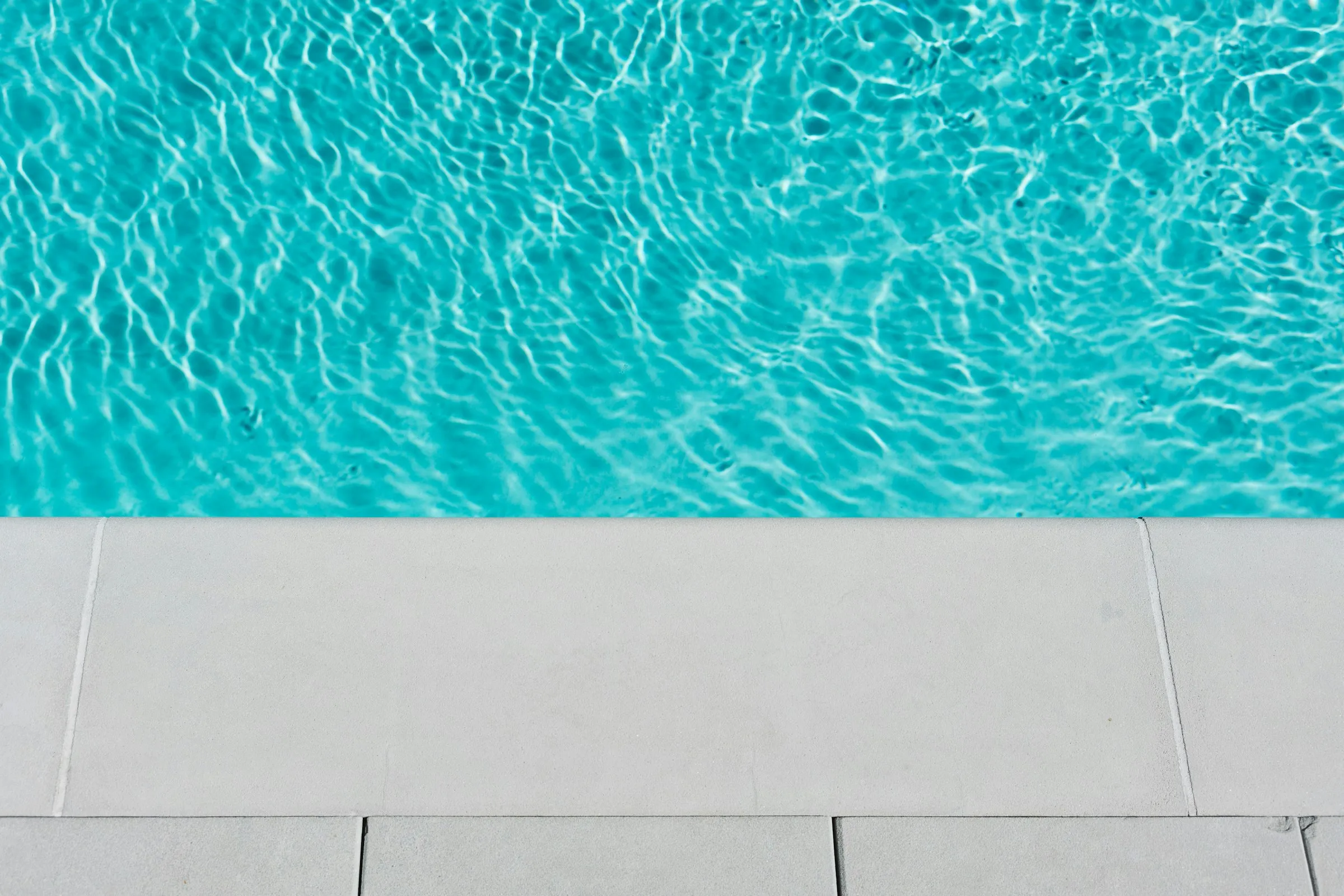 Borde atérmico blanco junto al agua de una piscina