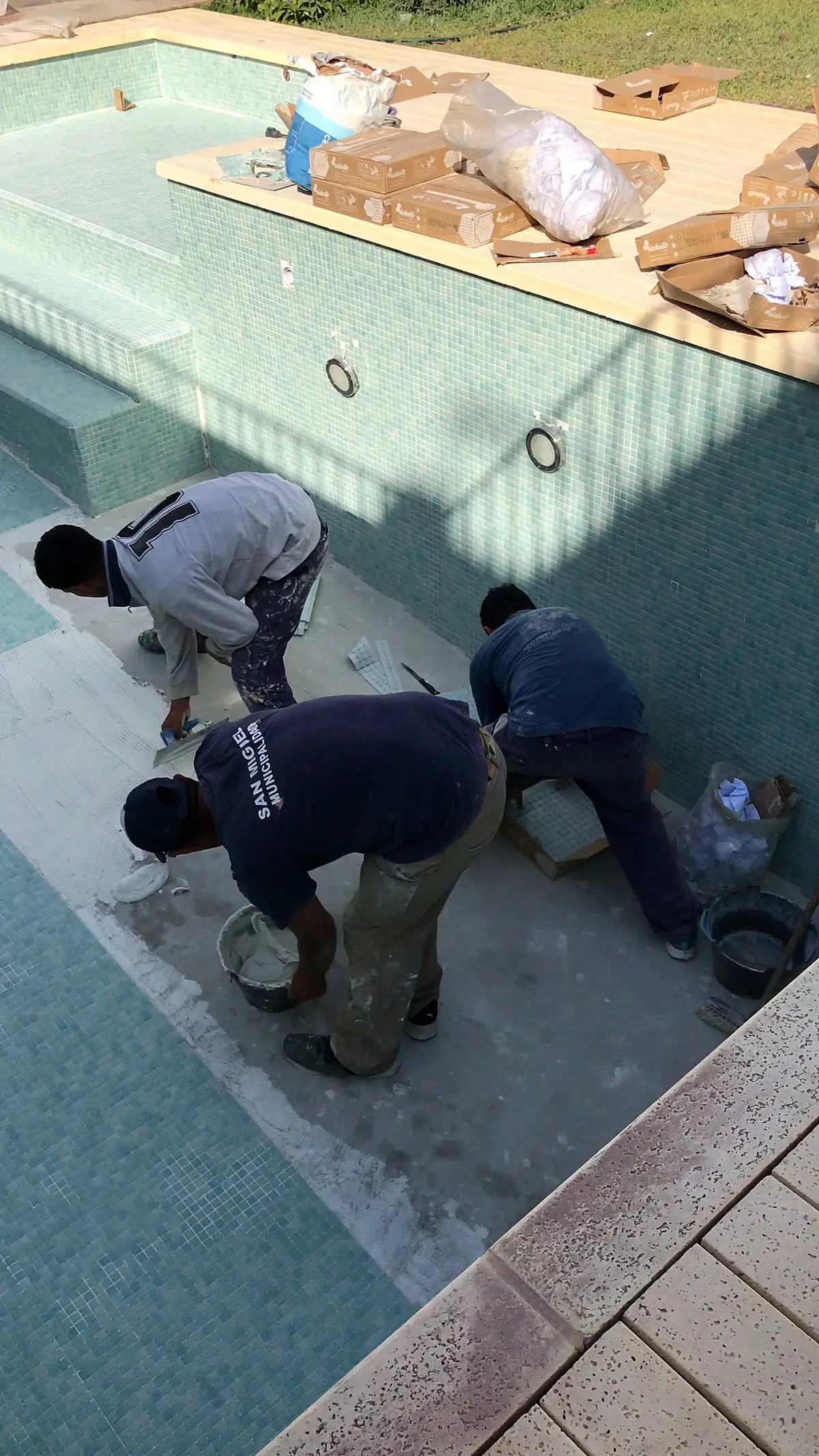 Equipo colocando el revestimiento de venecitas en el fondo de la piscina