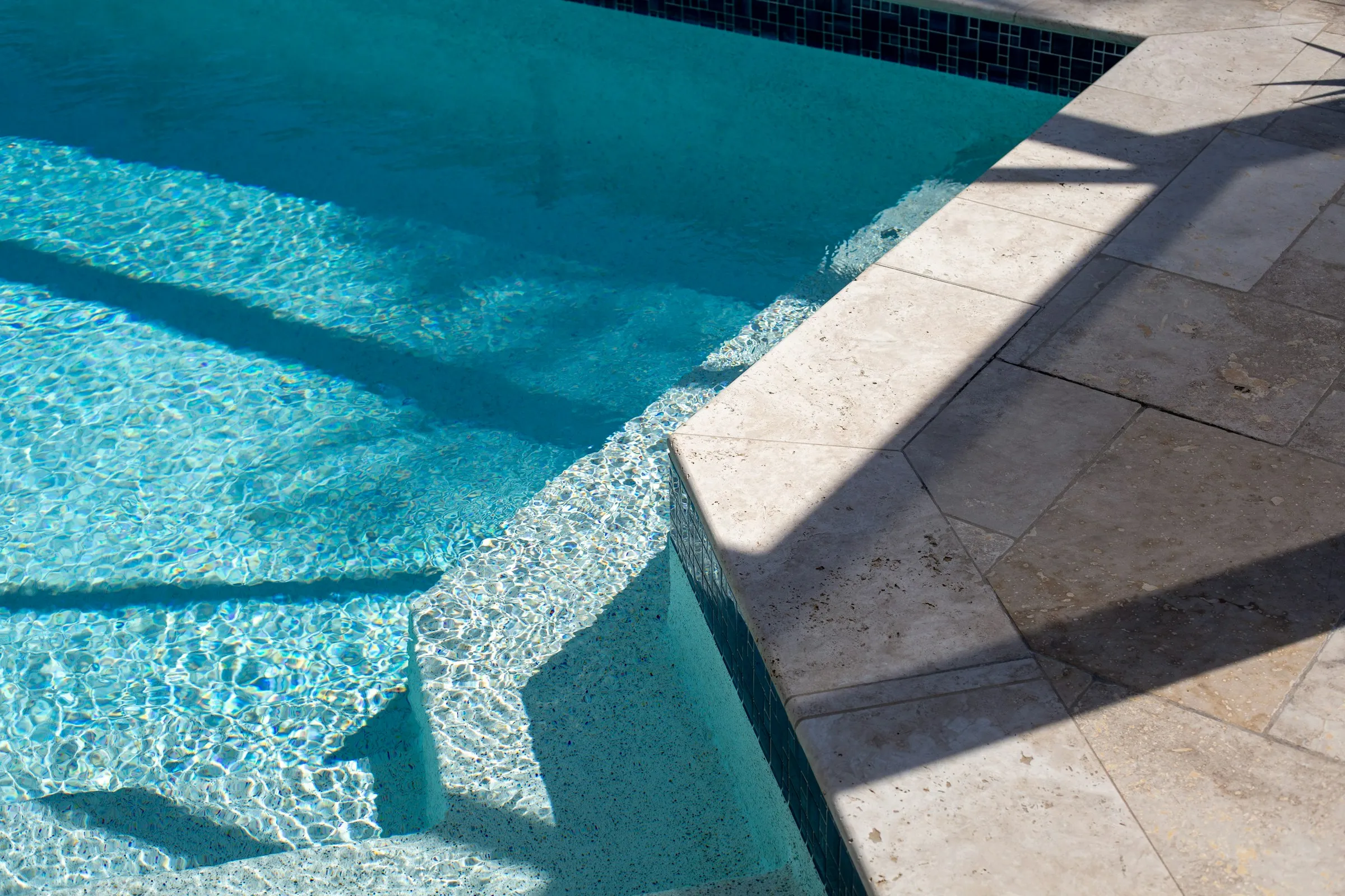 Borde de piscina con revestimiento celeste y agua cristalina