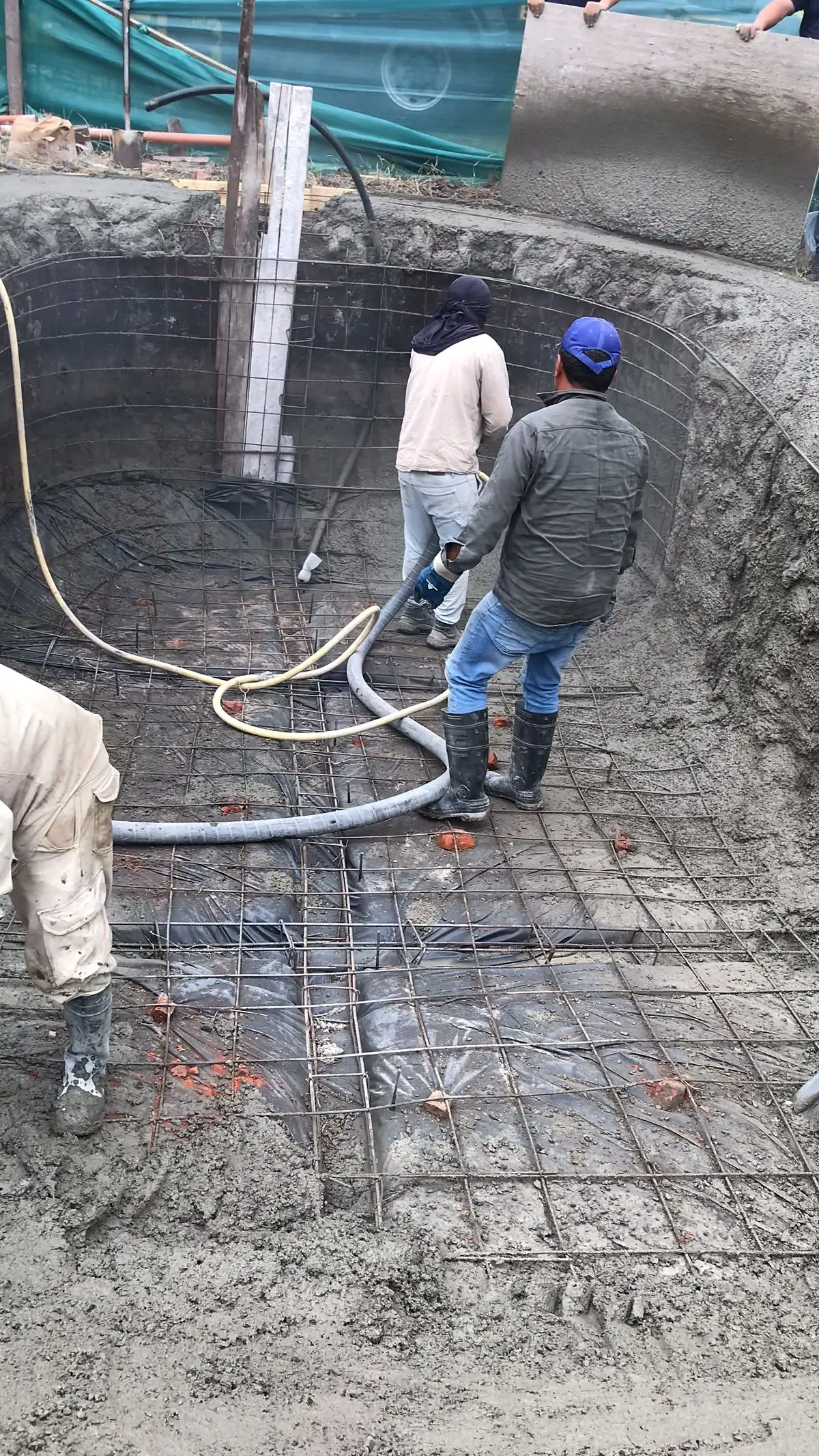 Equipo trabajando dentro de la piscina durante el hormigón proyectado