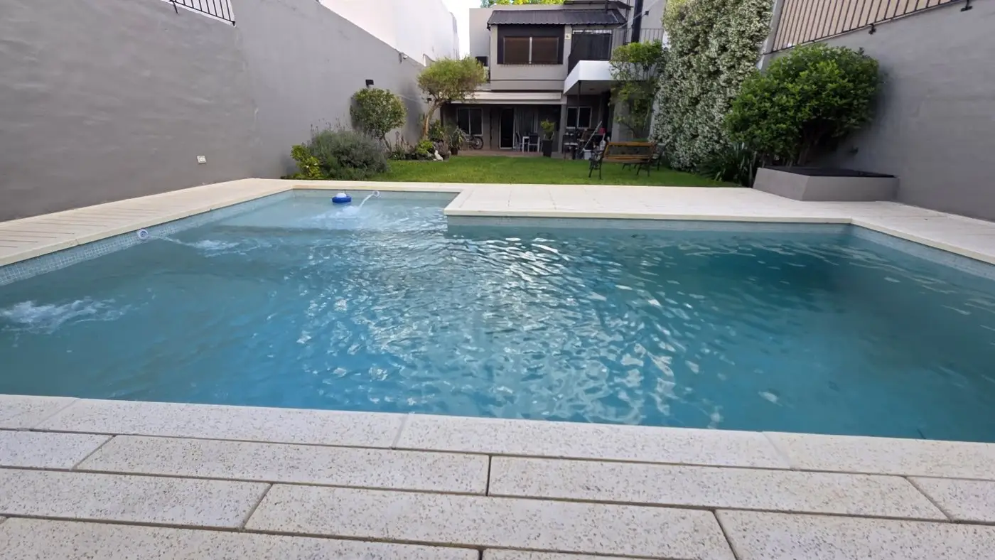 Piscina de Claudio Yegros con solárium claro y jardín