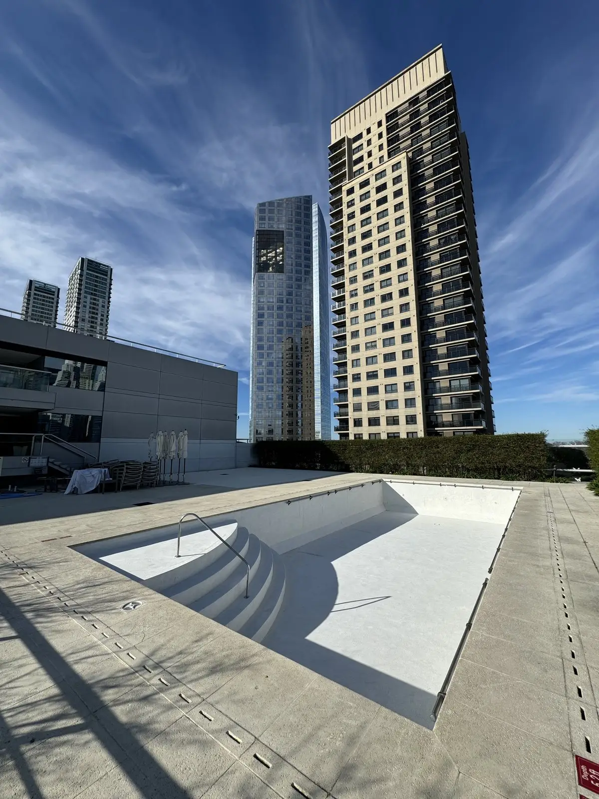 Piscina del hotel con la superficie blanca renovada en paredes, piso y escalones curvos, antes del llenado