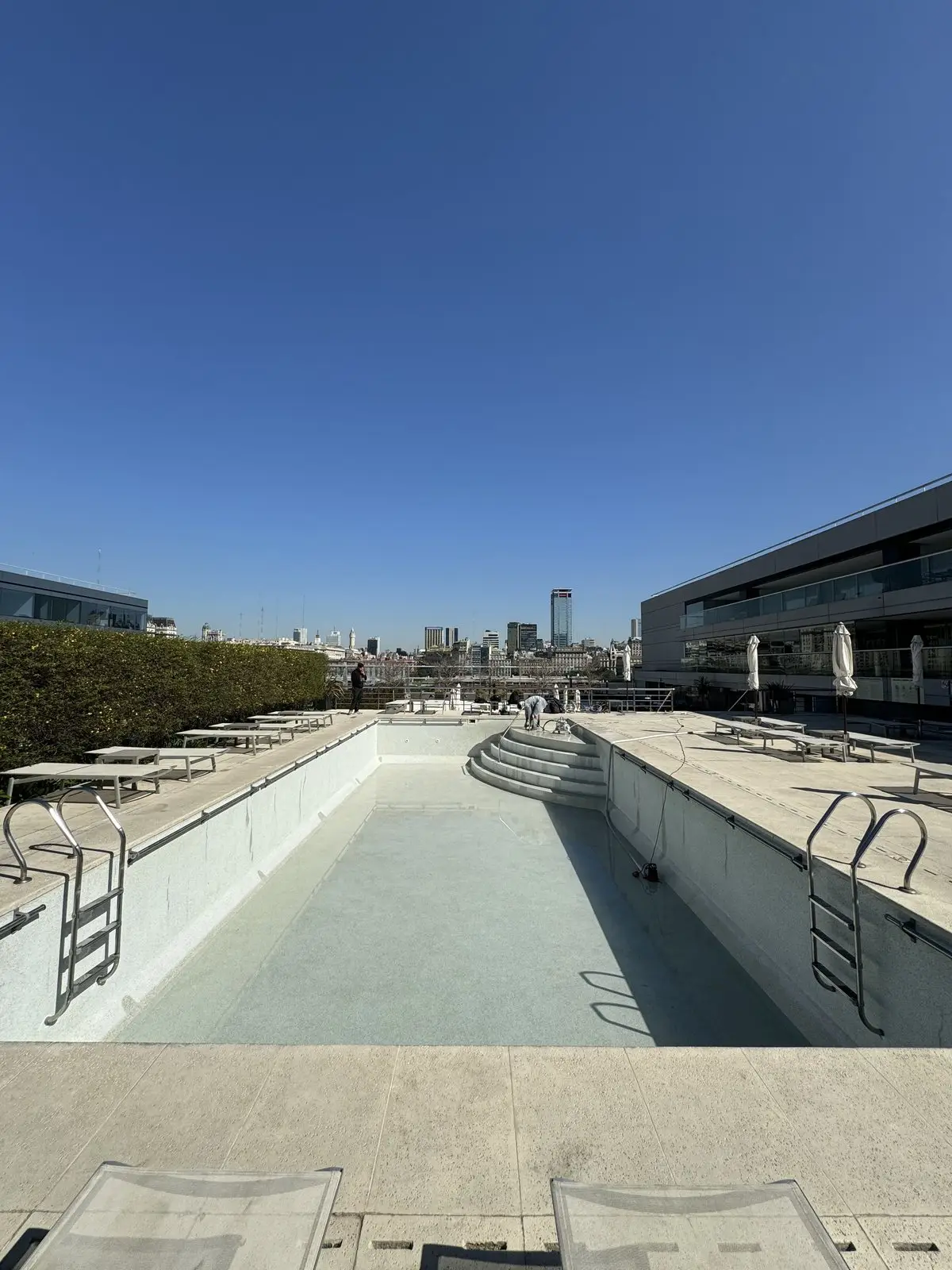 Piscina del hotel Hilton vacía antes de la renovación, con la superficie vieja manchada