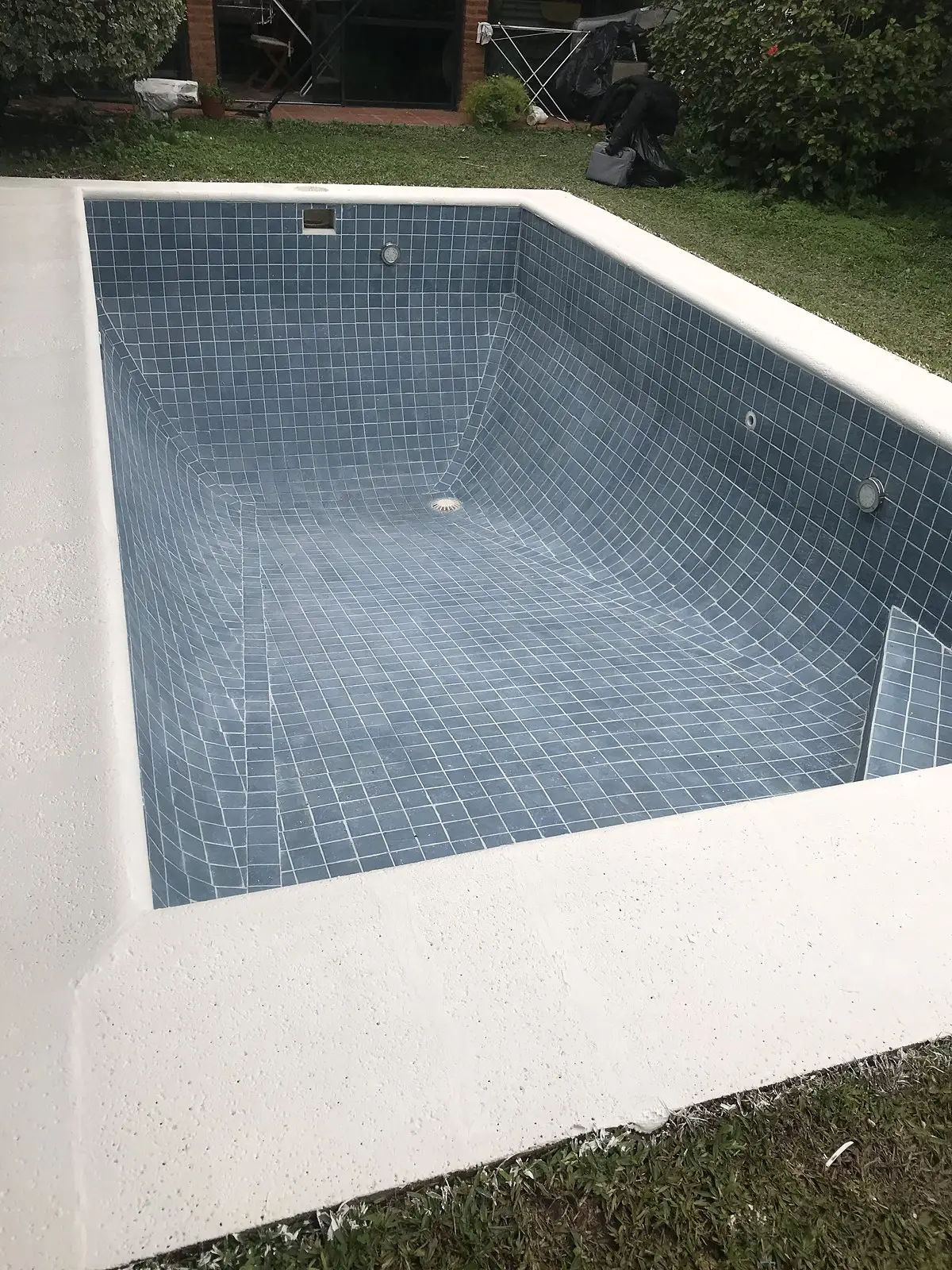 Piscina con el revestimiento nuevo terminado y el borde blanco, antes del llenado