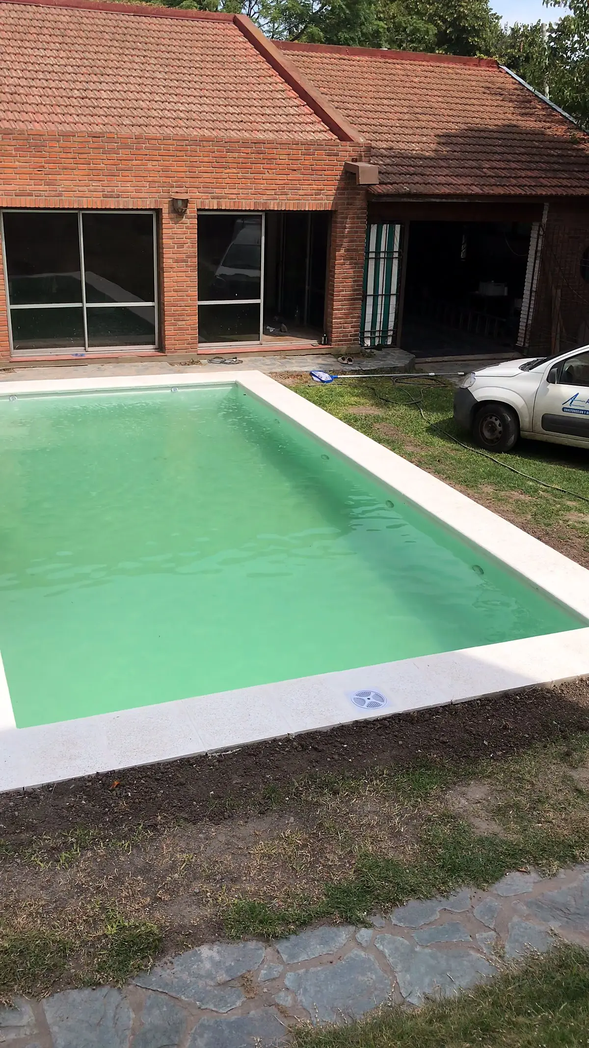 Piscina de hormigón terminada en el jardín, con el agua verde clara
