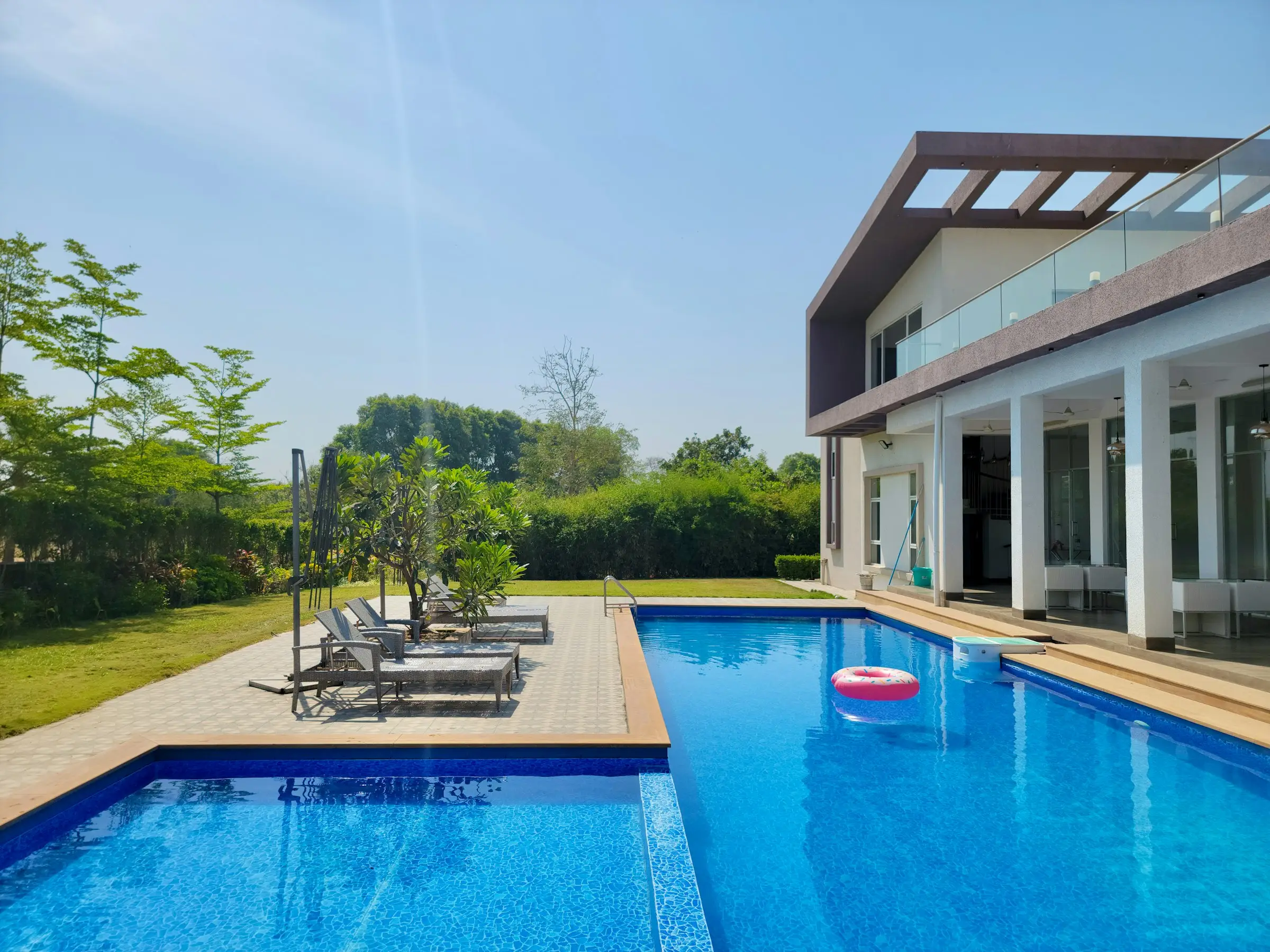 Piscina residencial de hormigón con revestimiento azul junto a una casa moderna