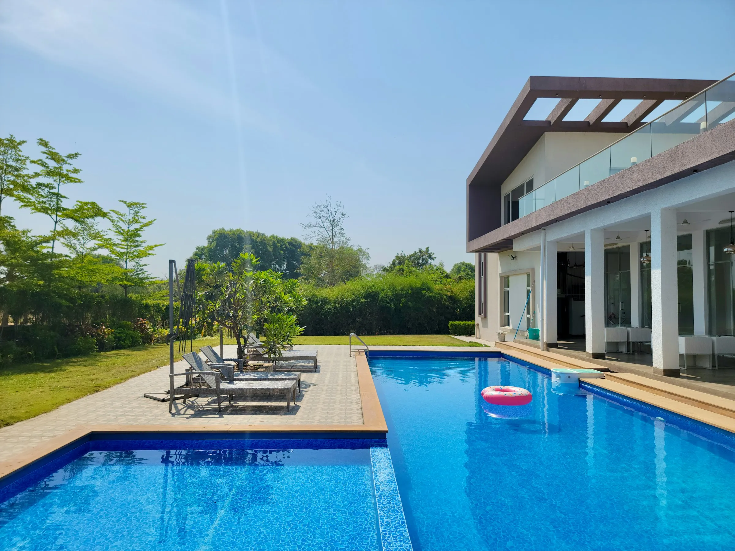 Piscina residencial de hormigón con revestimiento azul junto a una casa moderna