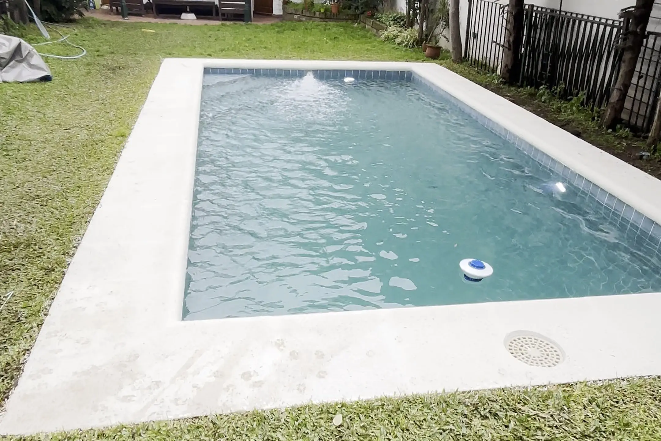 Piscina reformada en el jardín de una casa de Capital Federal, con borde blanco nuevo